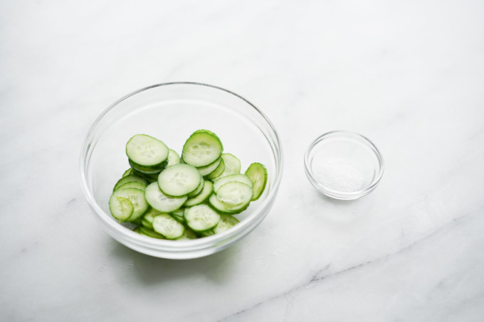 salt next to bowl of cucumber