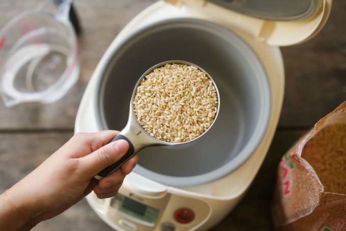 adding raw brown rice into rice cooker