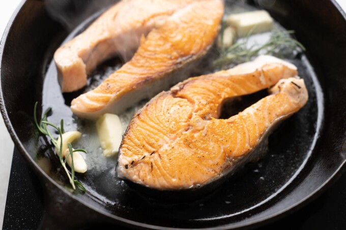 adding butter and herbs to salmon steaks