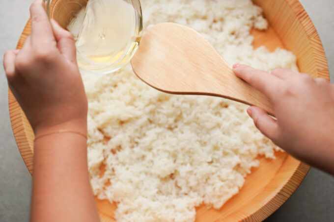 distributing sushi rice seasoning over rice