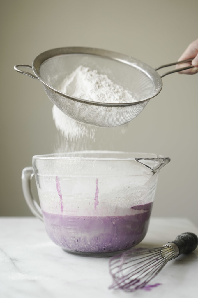 sifting flour into the bowl of batter