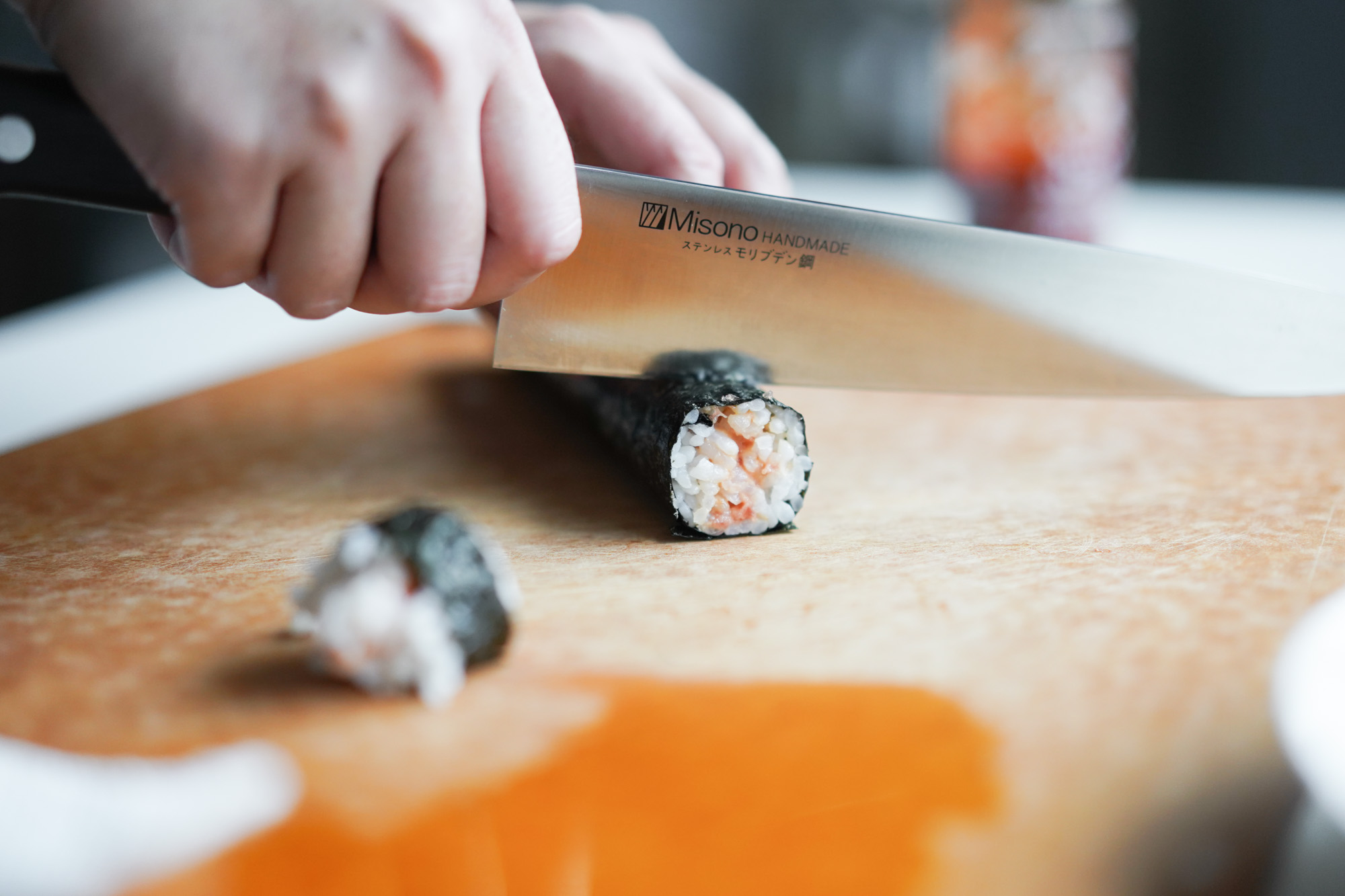 side view of chefs knife cutting a roll