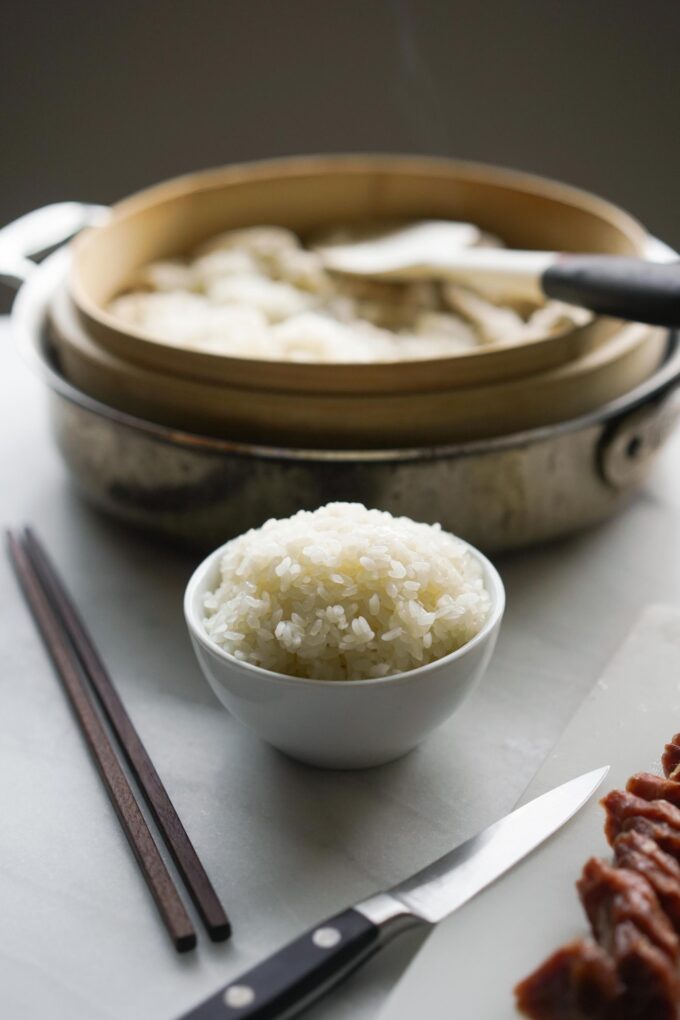 bowl of sticky rice next to bamboo steamer