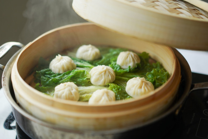 group of cooked xiao long bao in a bamboo steamer