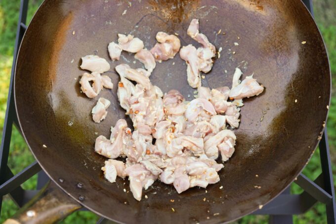 adding chicken to wok