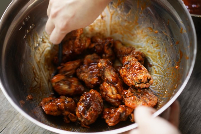 tossing chicken in the spicy sauce