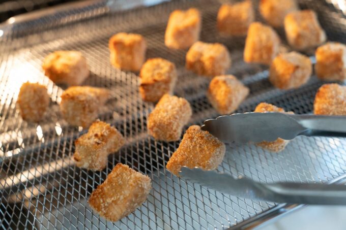 flipping over salmon cubes in air fryer basket