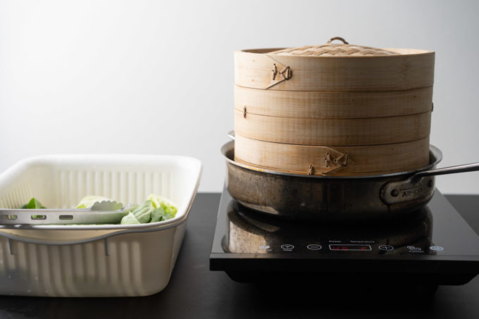 bamboo steamer on a stove and veggies